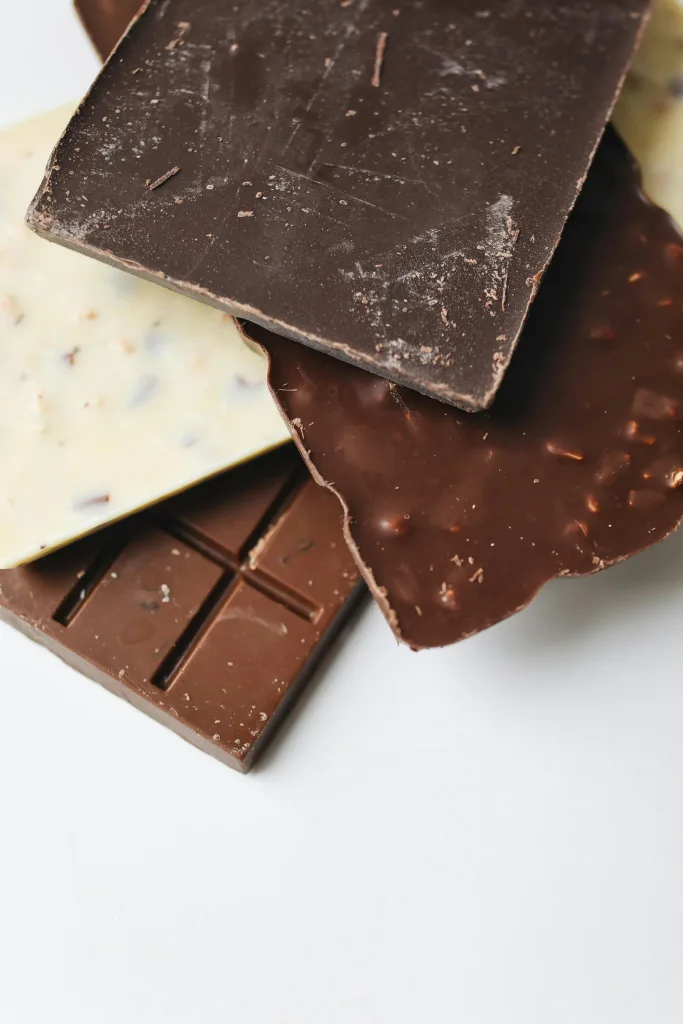 Verschillende soorten chocoladerepen op elkaar gestapeld. Het tempereren van chocolade is belangrijk om je dubai chocolade een goede houvast te geven.
